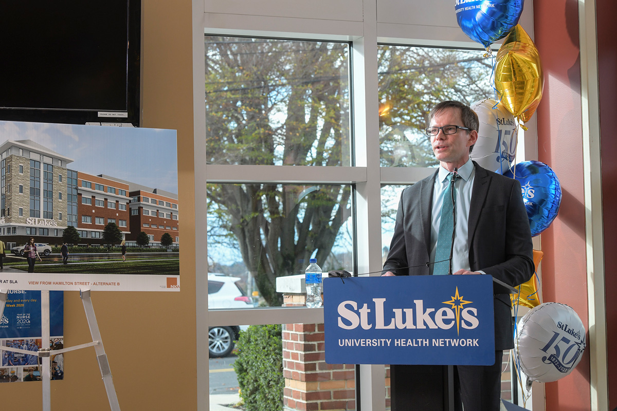 William Moyer, President of St. Luke’s Allentown Campus speaking behind a blue podium that says St. Luke's with a photo of the new Women and Babies Pavilion on easel