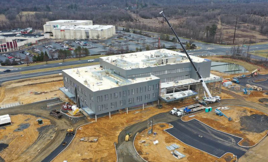 A drone shot of Good Shepherd's Rehabilitation Hospital featuring a large hospital facility with a gray brick facade surrounding with a crane in the front