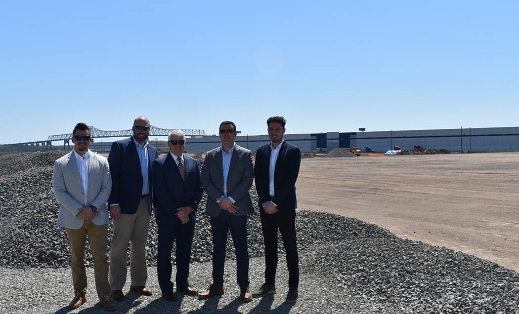 A group photo of IMC employees posing in front of the construction site of Bridgeport II