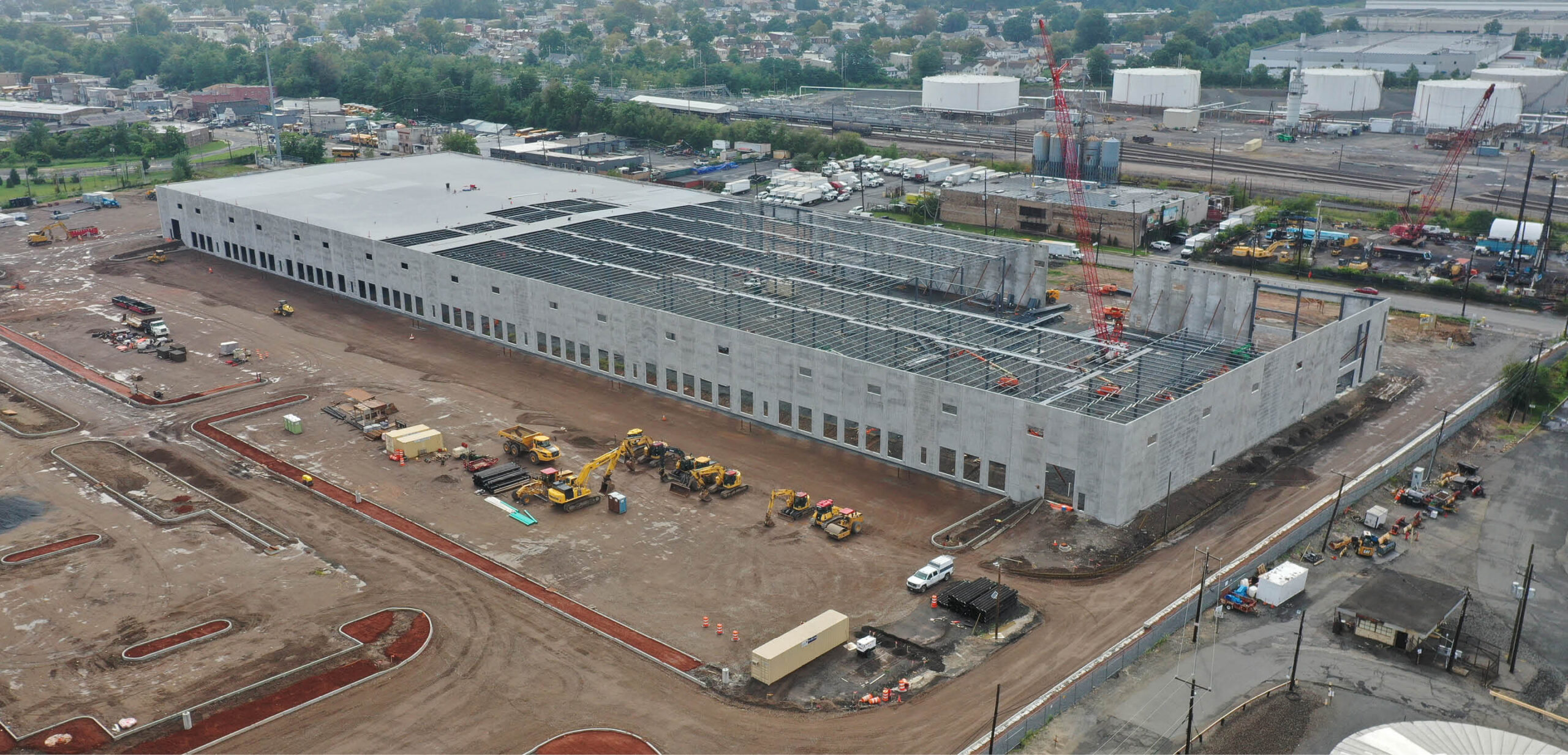 Warehouse being built by train tracks with construction equipment